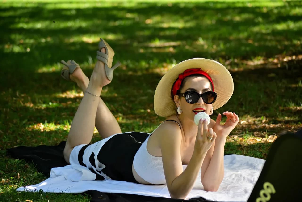 Pin-up-Picknick: Frau mit Strohhut und Sonnenbrille auf der Wiese