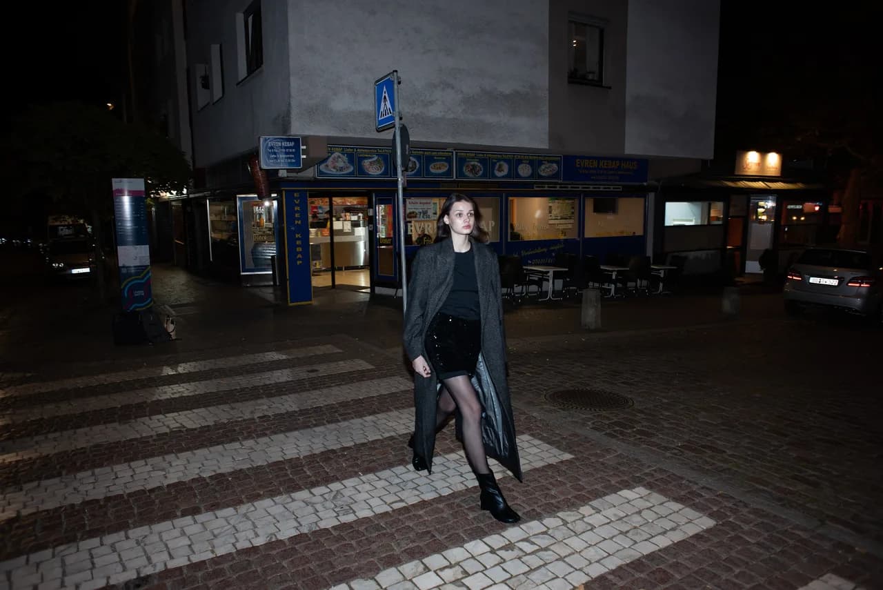 Frau überquert nachts einen Zebrastreifen in der Stadt